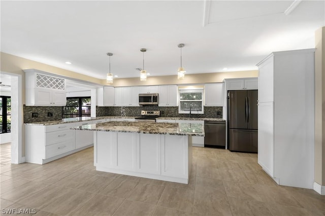 kitchen with hanging light fixtures, stone counters, white cabinetry, and appliances with stainless steel finishes