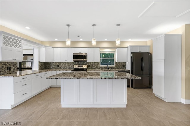 kitchen with white cabinets, stone countertops, appliances with stainless steel finishes, and pendant lighting