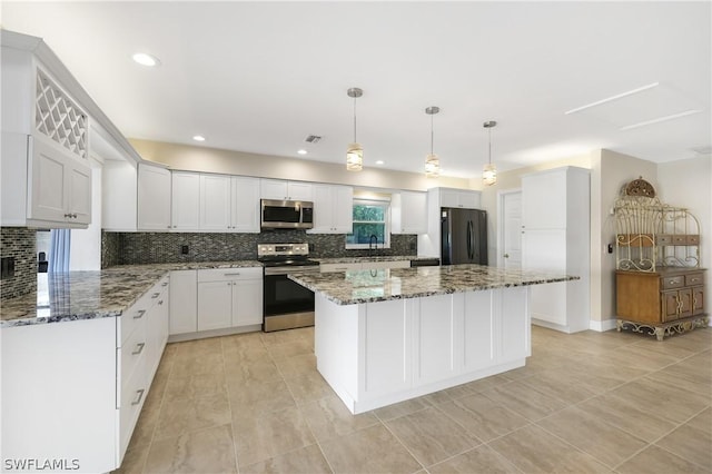 kitchen featuring stainless steel appliances, dark stone countertops, white cabinetry, and pendant lighting