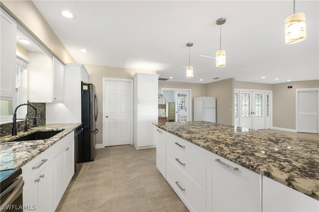 kitchen with stainless steel appliances, stone counters, white cabinetry, pendant lighting, and a sink