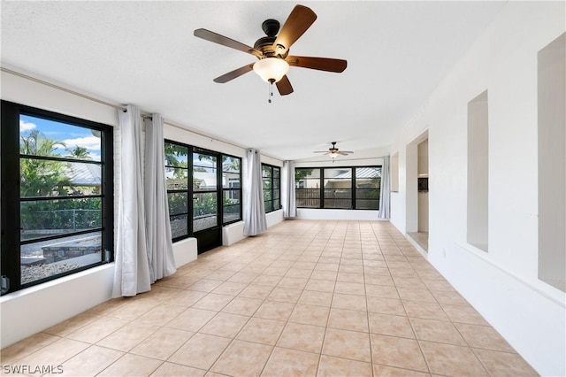 unfurnished sunroom featuring a healthy amount of sunlight and ceiling fan