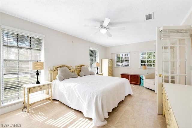 bedroom featuring light tile patterned floors, ceiling fan, visible vents, and a textured ceiling