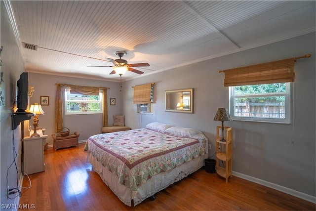 bedroom featuring hardwood / wood-style floors, multiple windows, ceiling fan, and ornamental molding