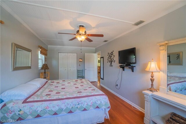 bedroom with ceiling fan, hardwood / wood-style flooring, crown molding, and a closet