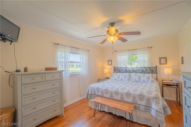 bedroom featuring multiple windows, crown molding, and light wood-type flooring