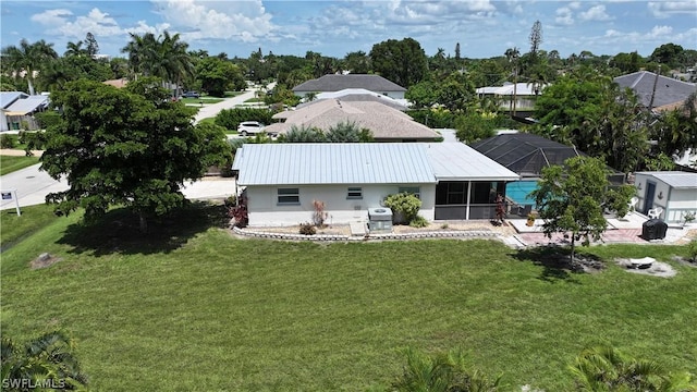 back of property featuring a lawn and a lanai