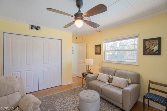 living room with hardwood / wood-style floors, ceiling fan, and ornamental molding