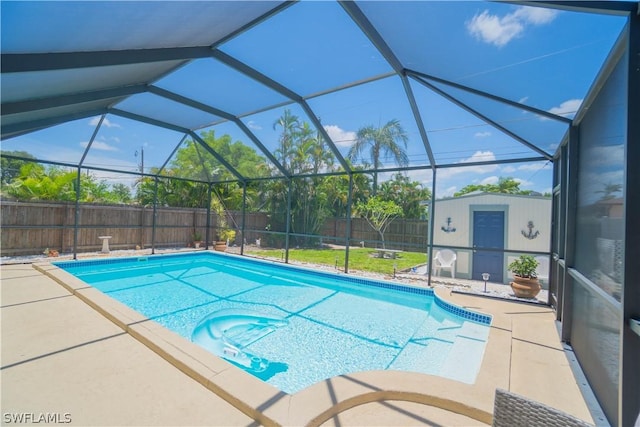 view of swimming pool featuring glass enclosure, a patio area, and a shed