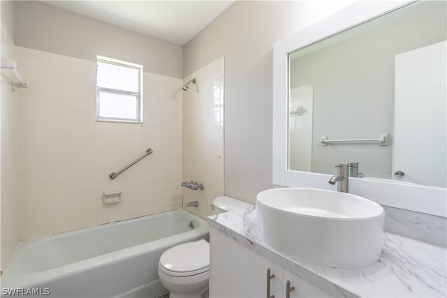 full bathroom featuring vanity, tiled shower / bath, and toilet