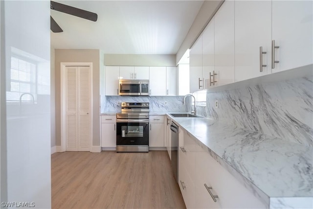 3325 Airport Rd N Unit S8, Naples, FL 34105 - kitchen with stainless steel appliances, a ceiling fan, backsplash, light wood-type flooring, and white cabinets