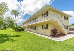 rear view of house featuring a balcony and a lawn