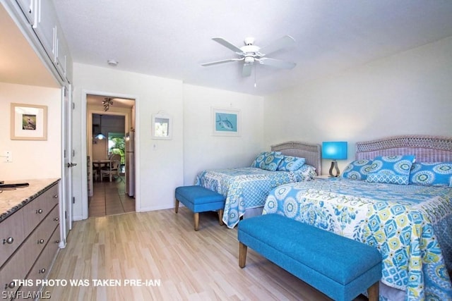 bedroom featuring ceiling fan, light hardwood / wood-style flooring, and stainless steel refrigerator