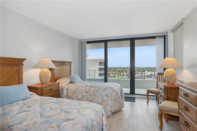 bedroom featuring light hardwood / wood-style floors, expansive windows, and access to outside