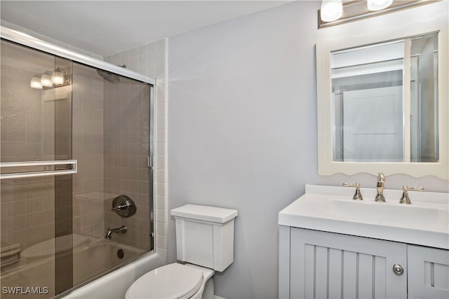 full bathroom with combined bath / shower with glass door, toilet, and vanity