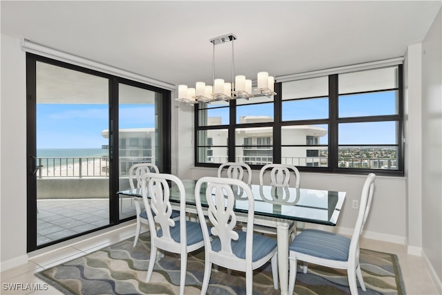 tiled dining room featuring an inviting chandelier and a water view