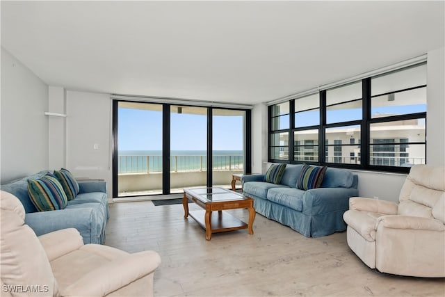 living room with a water view, light hardwood / wood-style flooring, and a wall of windows