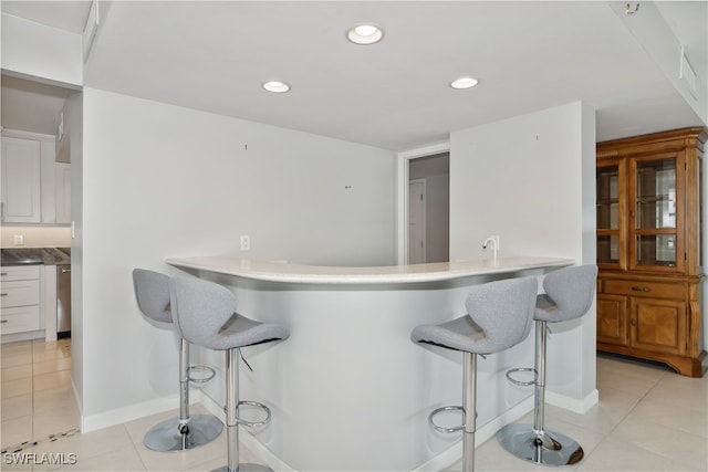 kitchen featuring white cabinets, a breakfast bar area, light tile patterned floors, and kitchen peninsula