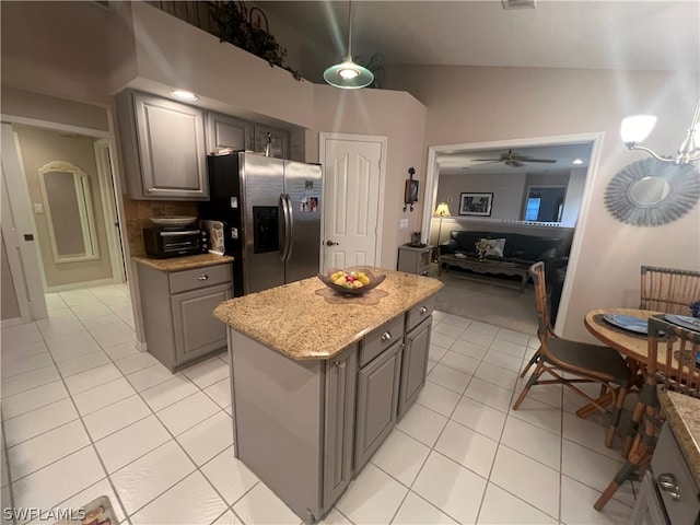 kitchen featuring stainless steel fridge, lofted ceiling, light tile patterned flooring, a center island, and ceiling fan