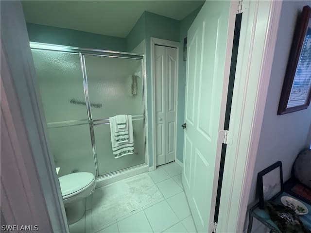 bathroom featuring tile patterned flooring, a shower with door, and toilet