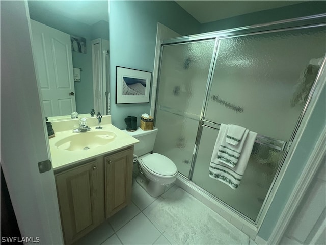 bathroom featuring a shower with shower door, vanity, tile patterned flooring, and toilet