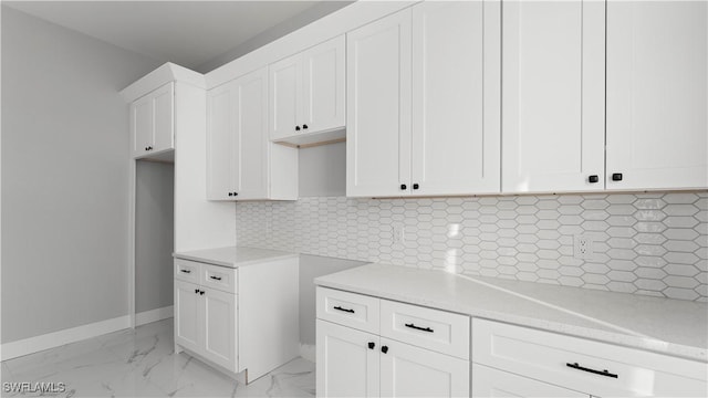 kitchen featuring decorative backsplash, light stone countertops, and white cabinetry