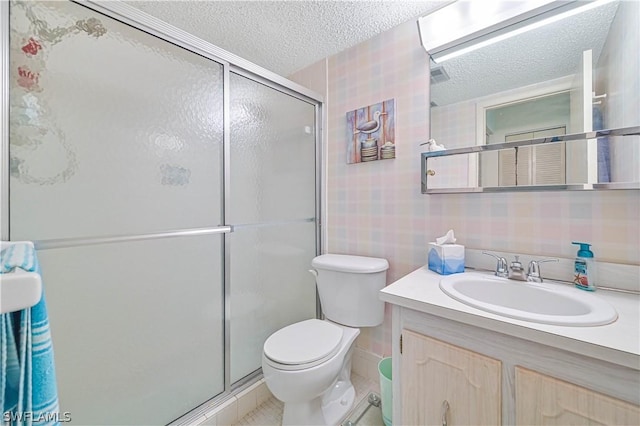 bathroom featuring vanity, a shower with door, toilet, and a textured ceiling