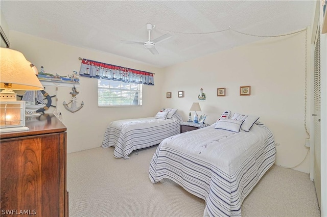 bedroom with ceiling fan, carpet, and a textured ceiling