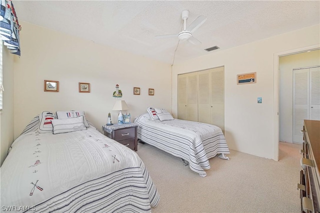 bedroom featuring ceiling fan, light carpet, a textured ceiling, and a closet