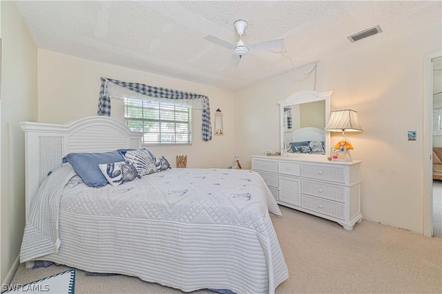 carpeted bedroom featuring ceiling fan and a textured ceiling