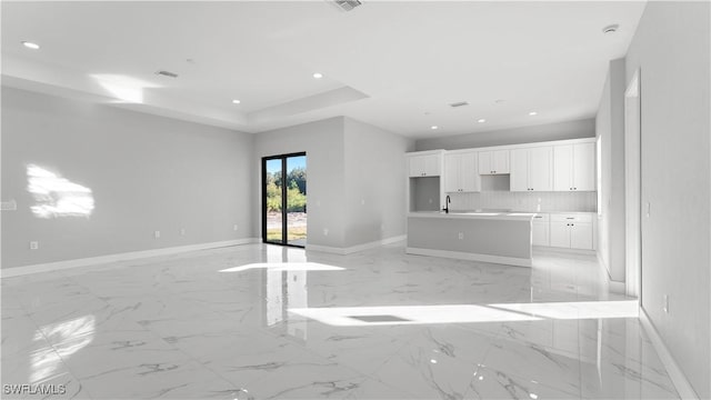 unfurnished living room featuring a tray ceiling and sink