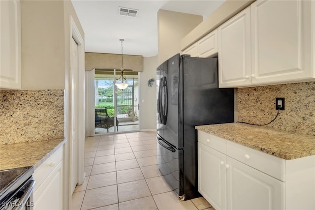 kitchen featuring black fridge, tasteful backsplash, light tile patterned floors, decorative light fixtures, and white cabinets