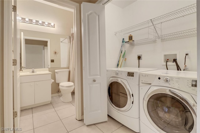 clothes washing area featuring washing machine and dryer, sink, and light tile patterned flooring