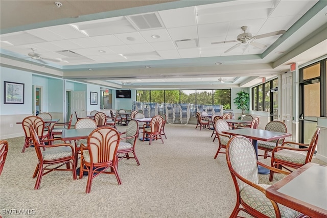 dining room with ceiling fan, light carpet, and a drop ceiling