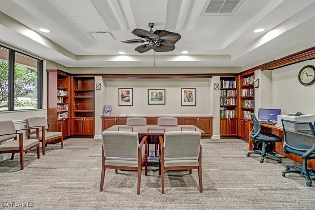 carpeted dining area with ceiling fan and a raised ceiling