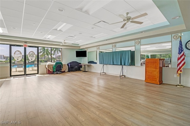 exercise room with a paneled ceiling, light wood-type flooring, and ceiling fan