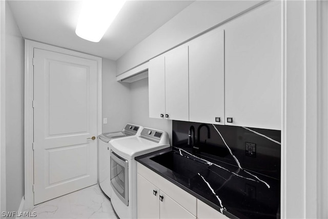 washroom with washing machine and clothes dryer, marble finish floor, and cabinet space