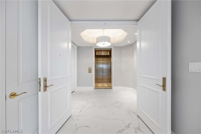 hallway with baseboards, marble finish floor, a tray ceiling, and a chandelier