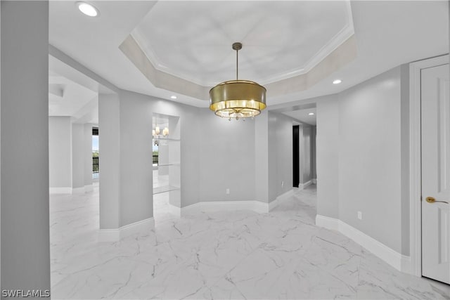 empty room featuring a raised ceiling, ornamental molding, and a chandelier