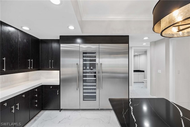 kitchen with stainless steel built in fridge, marble finish floor, crown molding, and dark cabinets