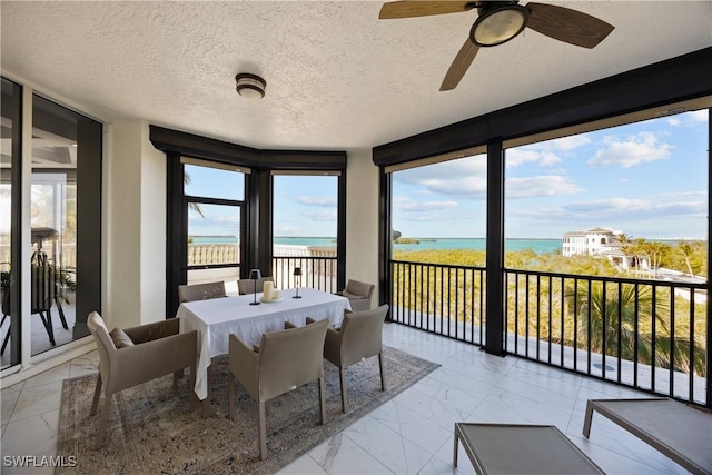 sunroom featuring a beach view and a water view