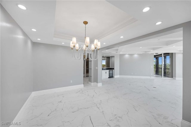 empty room featuring baseboards, a tray ceiling, and an inviting chandelier