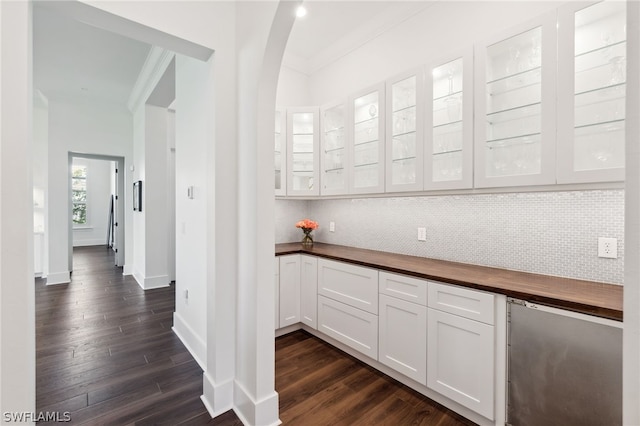 kitchen with dark hardwood / wood-style flooring, backsplash, crown molding, and white cabinets