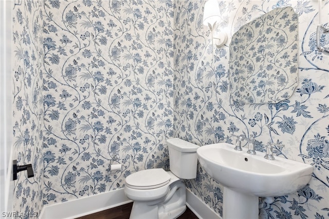 half bath featuring wallpapered walls, toilet, baseboards, and wood finished floors