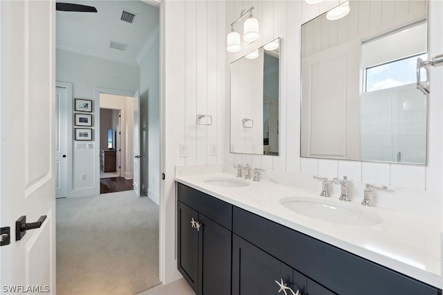 bathroom featuring crown molding, double vanity, visible vents, and a sink