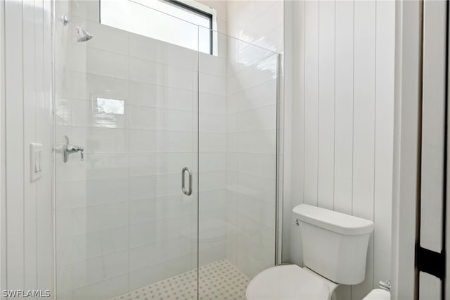 bathroom featuring a shower with door and toilet