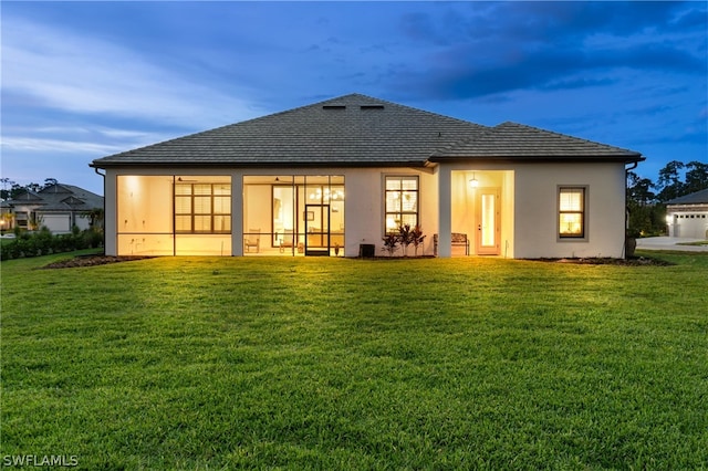 rear view of house featuring a lawn and stucco siding