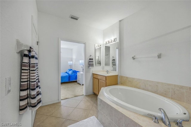 bathroom with tile patterned flooring, vanity, and a relaxing tiled tub