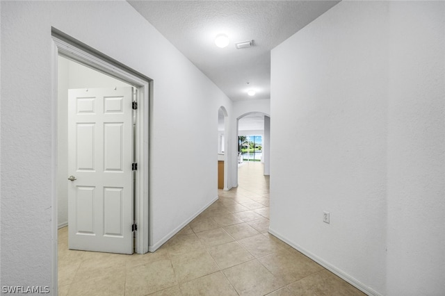 hall with light tile patterned floors and a textured ceiling