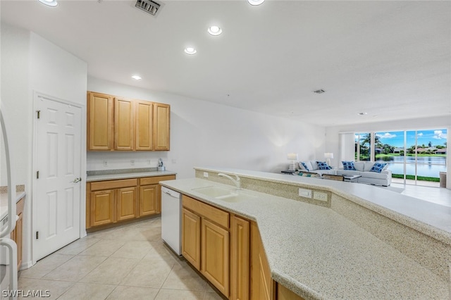 kitchen with sink, light stone counters, light brown cabinets, light tile patterned floors, and white dishwasher