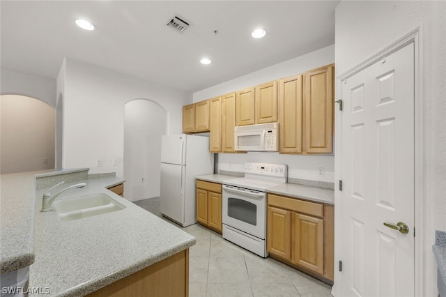 kitchen featuring sink, white appliances, light stone counters, light tile patterned flooring, and light brown cabinets